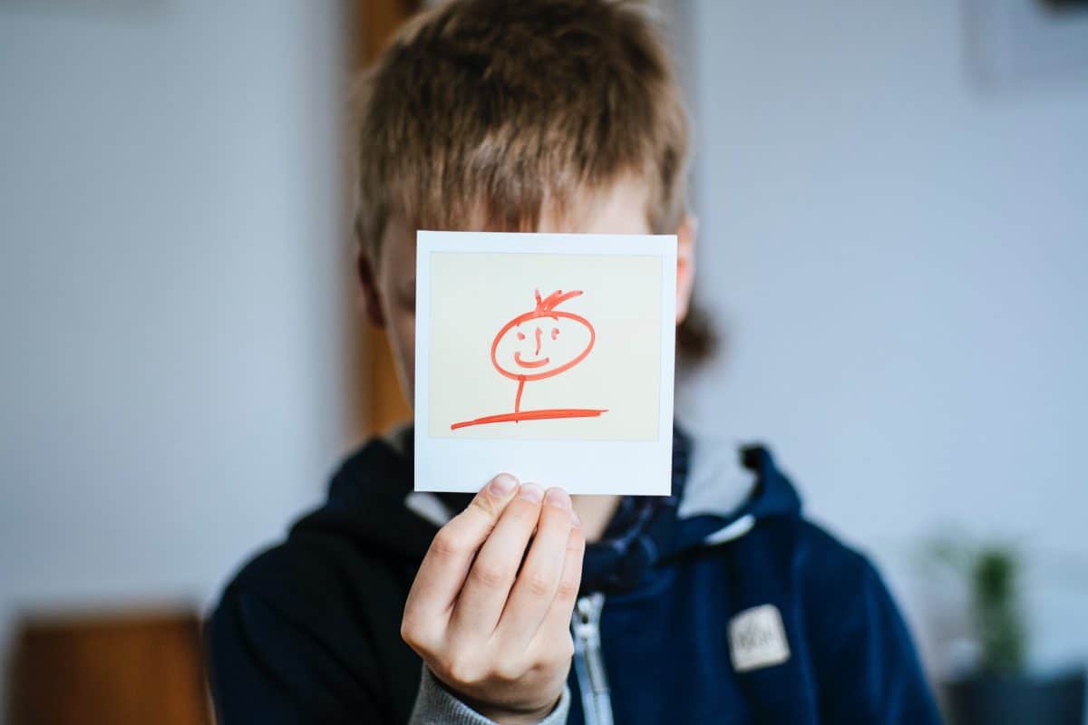 Kind hält Polaroid mit Strichmann-Gesicht vors Gesicht. Quelle: pexels.com
